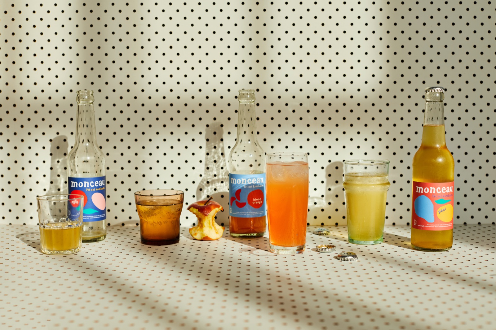 Bottles and glasses lined up in sunlight on a polka‑dot cloth