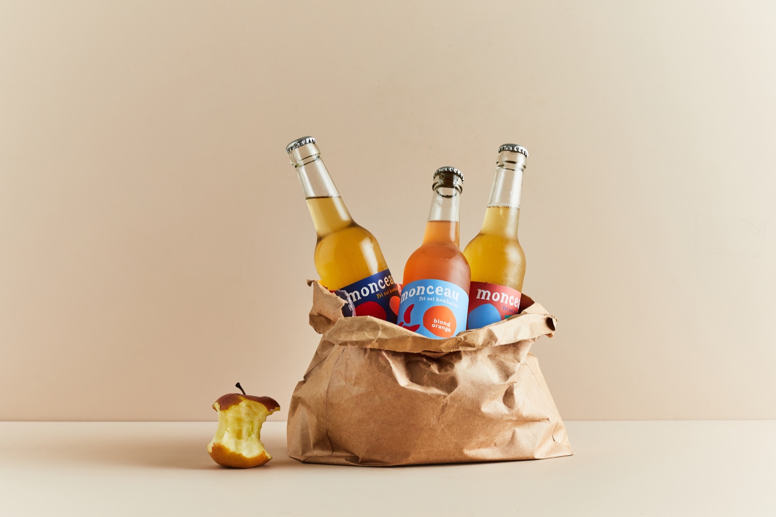 A paper bag of ice holding three bottles of Monceau, with radishes and a pear